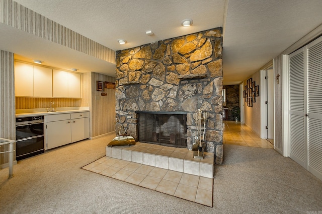 carpeted living room featuring indoor wet bar, a stone fireplace, and a textured ceiling