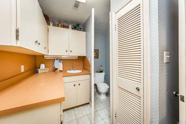 bathroom with tile patterned floors, toilet, vanity, and a textured ceiling