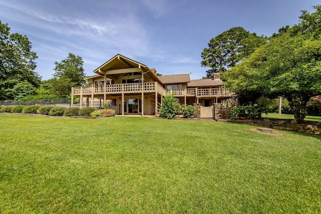 rear view of house with a wooden deck and a lawn