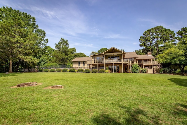 back of house with a wooden deck and a lawn