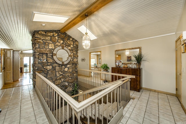 hallway featuring vaulted ceiling with skylight and light tile patterned flooring