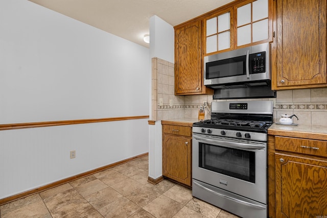 kitchen with decorative backsplash, stainless steel appliances, tile counters, and light tile patterned floors