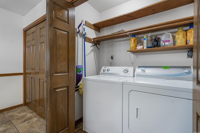 clothes washing area featuring separate washer and dryer, light tile patterned flooring, and a textured ceiling