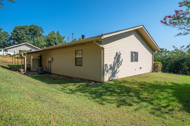 view of side of property with central AC and a yard