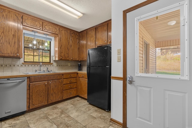 kitchen with sink, backsplash, black refrigerator, light tile patterned floors, and stainless steel dishwasher