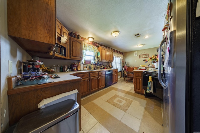 kitchen featuring a textured ceiling, visible vents, light countertops, brown cabinets, and black appliances