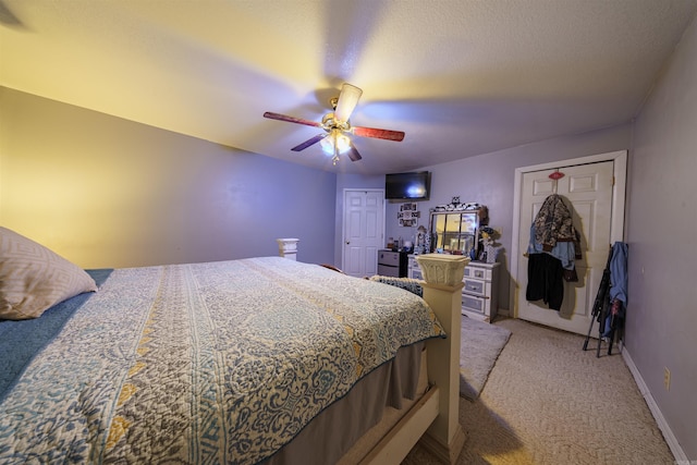 bedroom featuring ceiling fan, baseboards, a textured ceiling, and light colored carpet