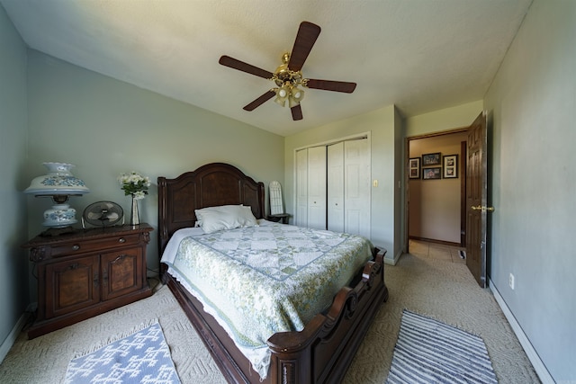 bedroom featuring ceiling fan, a closet, light carpet, and baseboards