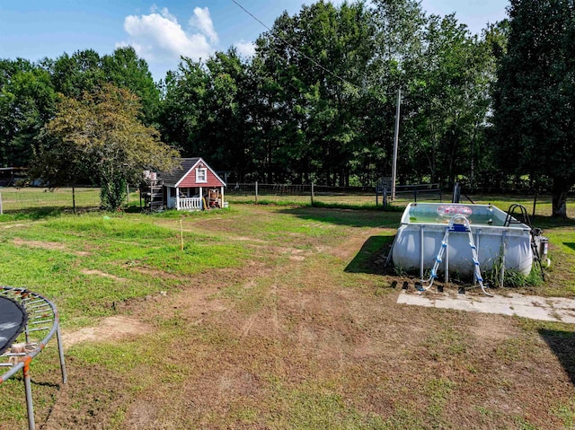 view of yard featuring an outdoor structure, an empty pool, and fence