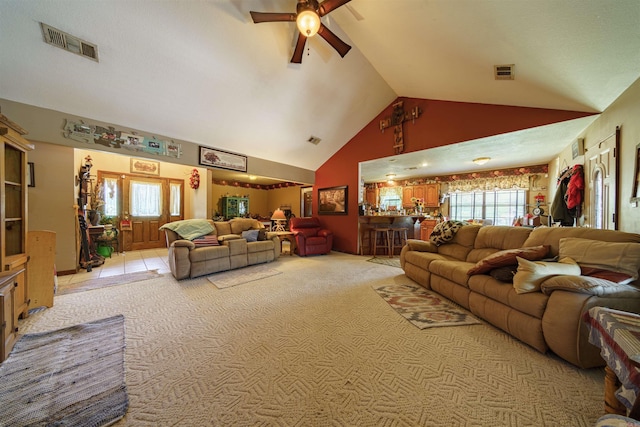 living area with high vaulted ceiling, visible vents, and light colored carpet