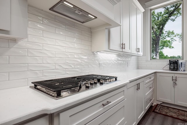 kitchen with stainless steel gas stovetop, tasteful backsplash, white cabinets, dark wood-type flooring, and range hood