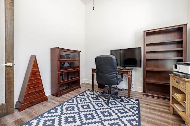 office area with a high ceiling and light hardwood / wood-style floors