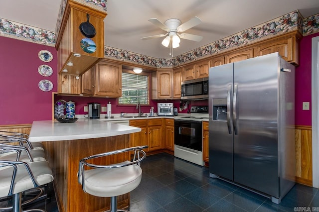 kitchen with a breakfast bar area, kitchen peninsula, ceiling fan, stainless steel appliances, and sink