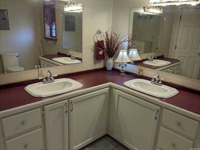 bathroom with double sink vanity, toilet, electric panel, and tile patterned flooring