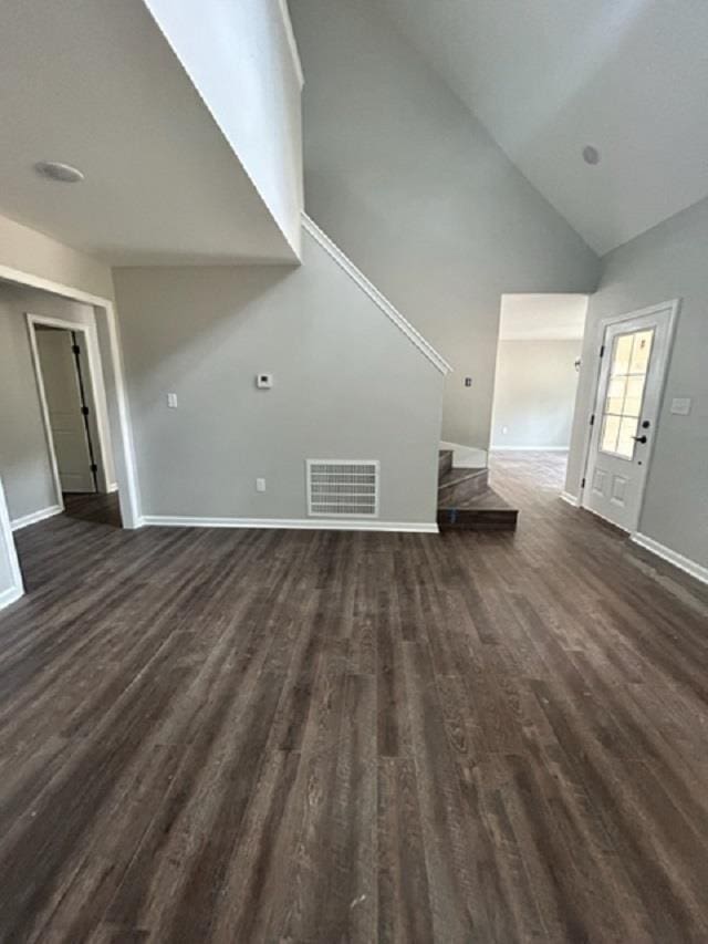 unfurnished living room featuring dark wood-type flooring and high vaulted ceiling