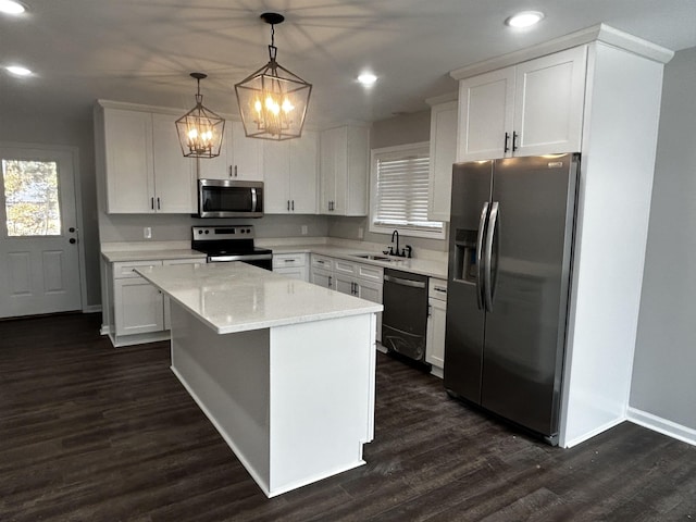 kitchen with hanging light fixtures, a kitchen island, appliances with stainless steel finishes, and white cabinets