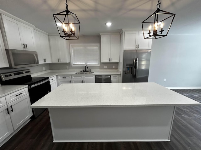 kitchen featuring light stone counters, appliances with stainless steel finishes, hanging light fixtures, and a kitchen island