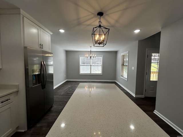 kitchen with pendant lighting, white cabinetry, light stone counters, stainless steel fridge with ice dispenser, and an inviting chandelier