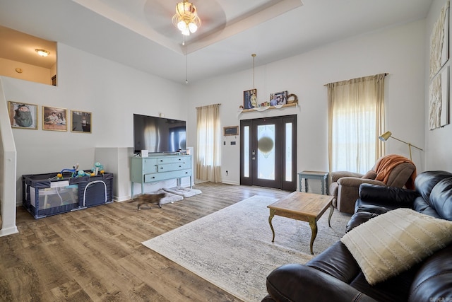 living room with ceiling fan, hardwood / wood-style flooring, and a tray ceiling