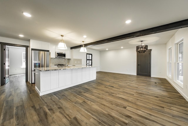 kitchen with decorative light fixtures, white cabinetry, light stone counters, stainless steel appliances, and beam ceiling