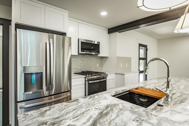 kitchen featuring light stone counters, stainless steel appliances, sink, and white cabinets