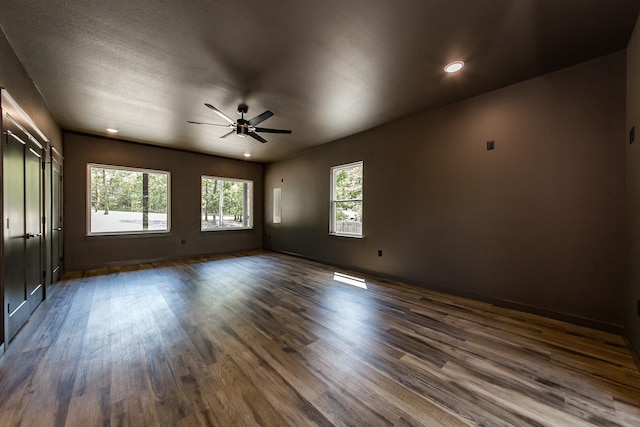 spare room featuring ceiling fan, a healthy amount of sunlight, and dark hardwood / wood-style flooring