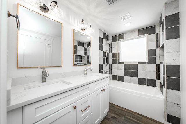 bathroom with vanity, wood-type flooring, and tiled shower / bath