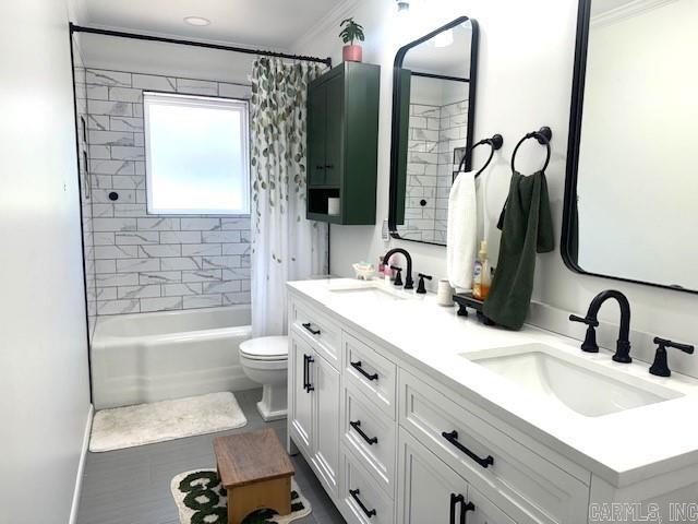 full bathroom with toilet, shower / tub combo, double vanity, and a sink