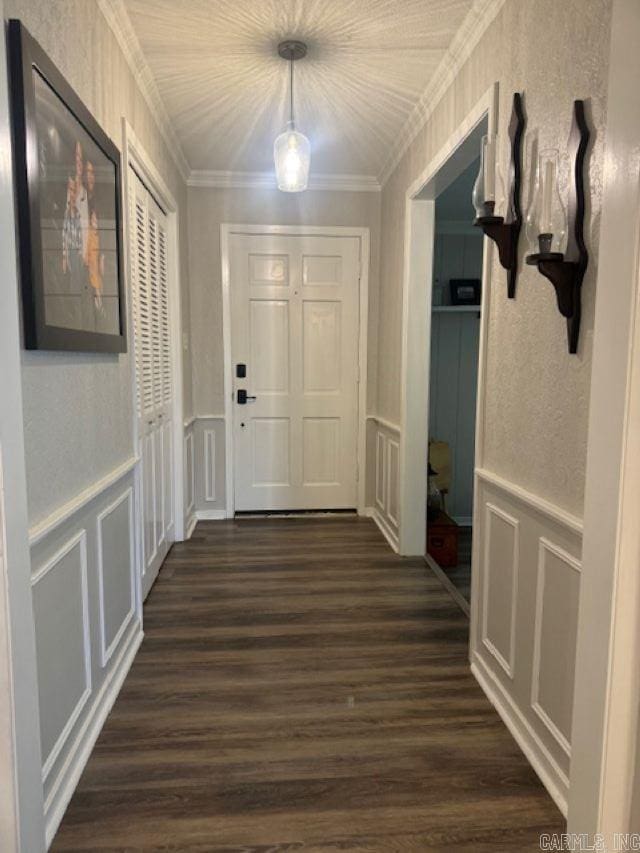 corridor with dark wood-style floors, a decorative wall, crown molding, and a wainscoted wall