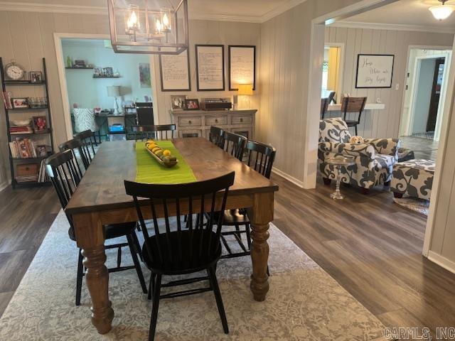 dining room with dark wood-style floors, crown molding, and baseboards