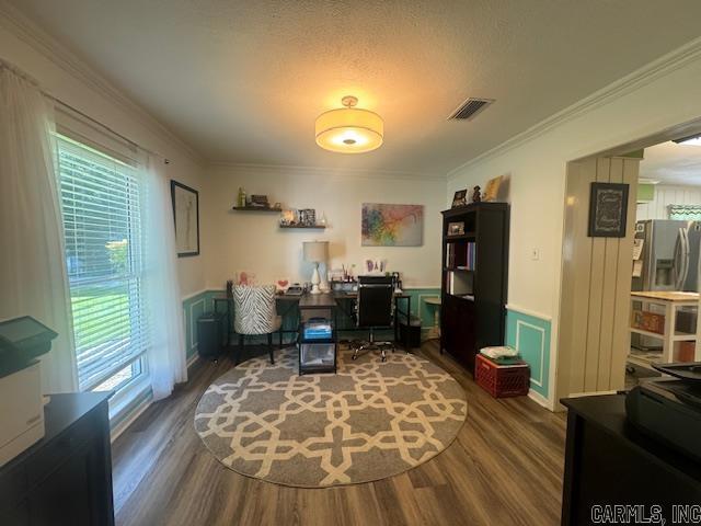 home office with visible vents, dark wood-style floors, a wainscoted wall, crown molding, and a decorative wall