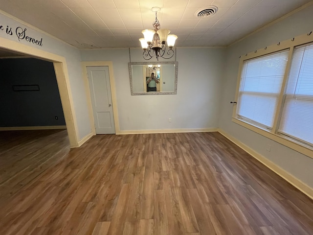 unfurnished room with crown molding, a notable chandelier, and hardwood / wood-style flooring