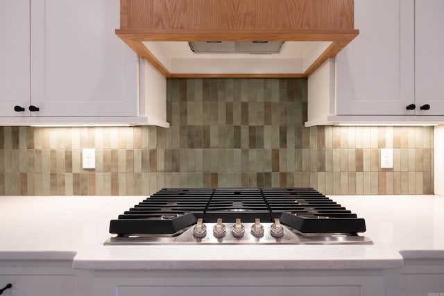 room details featuring stainless steel gas stovetop, white cabinetry, and backsplash