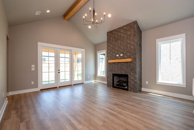 unfurnished living room with light hardwood / wood-style flooring, beam ceiling, a fireplace, french doors, and a chandelier