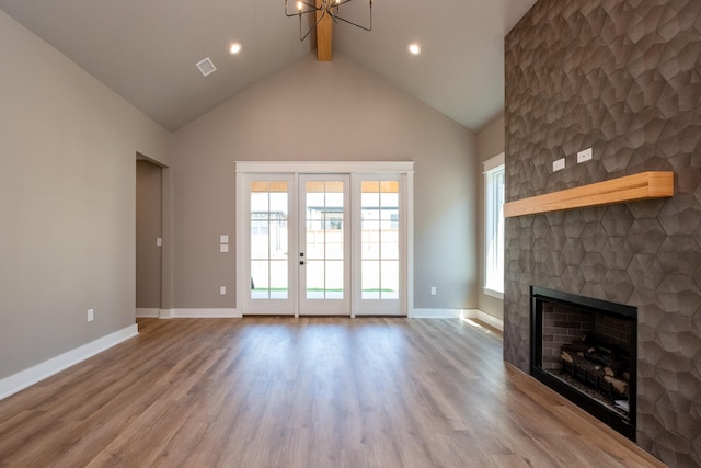 unfurnished living room with beam ceiling, high vaulted ceiling, and light hardwood / wood-style flooring