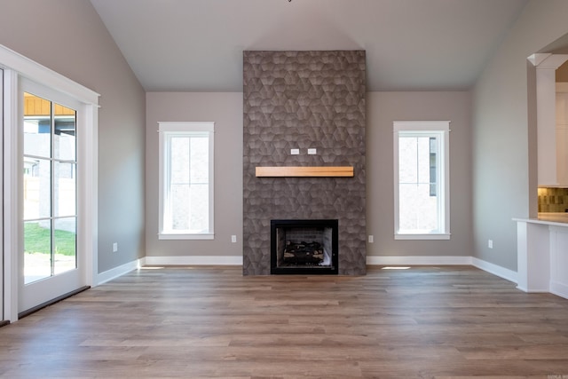 unfurnished living room with lofted ceiling, light wood-type flooring, and a fireplace