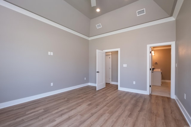 unfurnished bedroom with a towering ceiling and light hardwood / wood-style floors