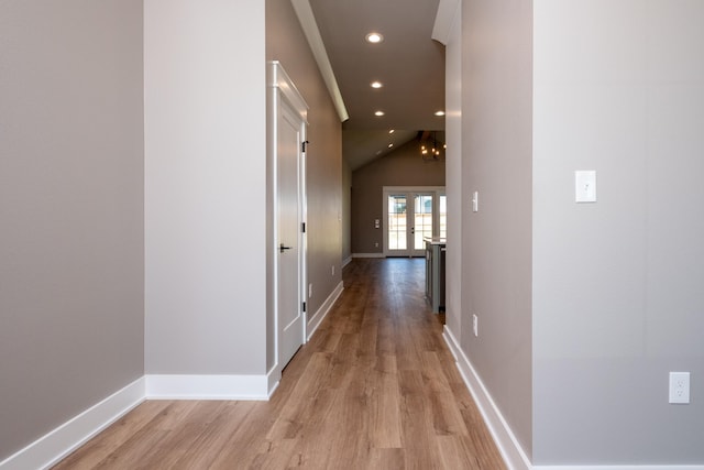 corridor with vaulted ceiling and light hardwood / wood-style flooring