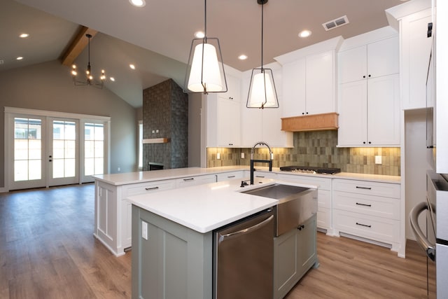 kitchen with white cabinetry, stainless steel appliances, kitchen peninsula, and a center island with sink