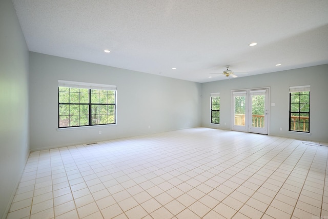 unfurnished room with light tile patterned floors, ceiling fan, and a textured ceiling