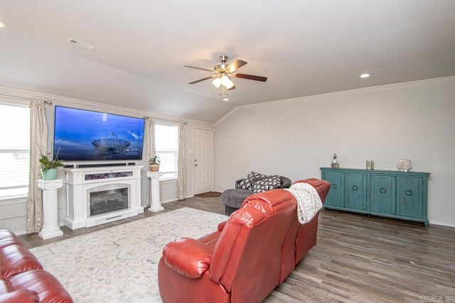 living room featuring crown molding, wood-type flooring, vaulted ceiling, ceiling fan, and a fireplace