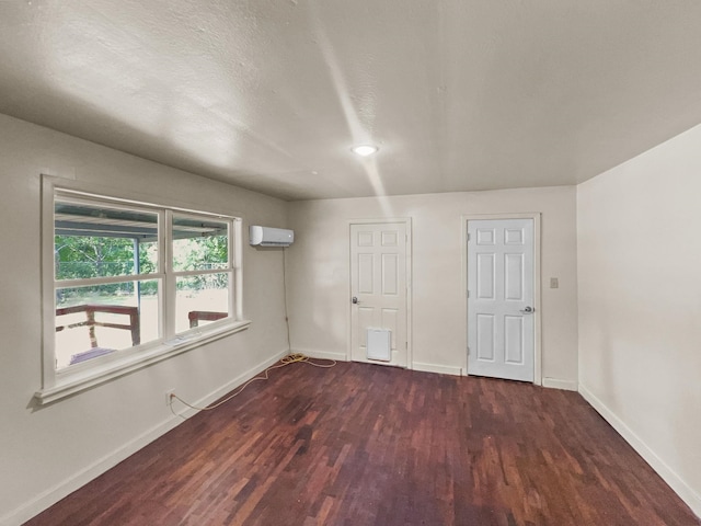 spare room featuring an AC wall unit and dark hardwood / wood-style floors