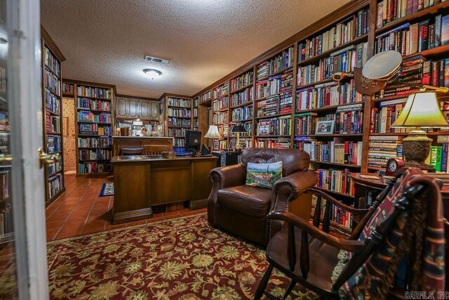 living area with dark tile patterned flooring, a textured ceiling, and crown molding