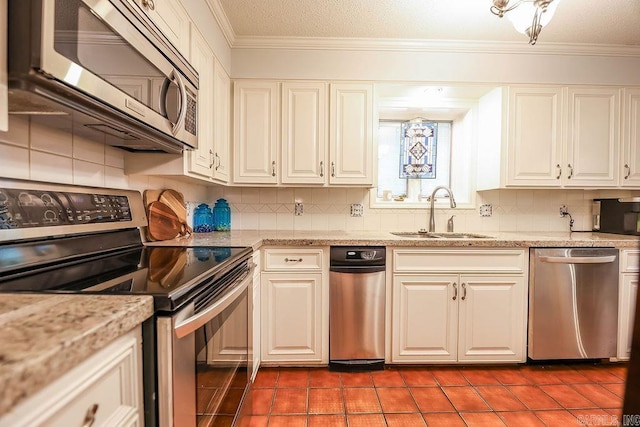 kitchen with appliances with stainless steel finishes, tile patterned floors, backsplash, ornamental molding, and sink