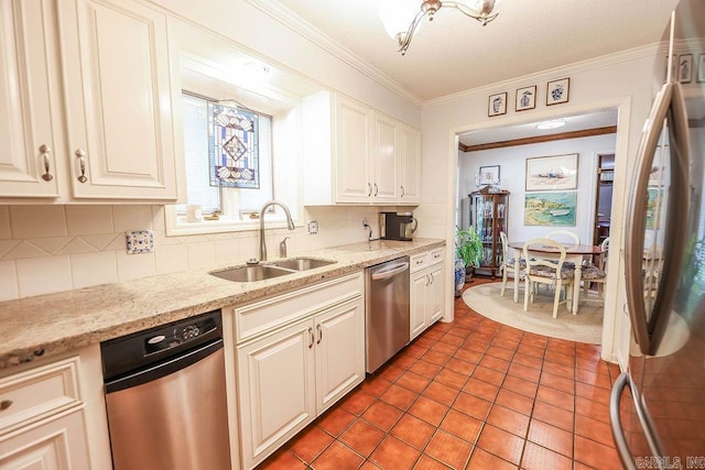 kitchen featuring crown molding, stainless steel appliances, light stone countertops, sink, and tile patterned floors