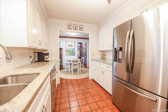 kitchen with stainless steel appliances, white cabinets, sink, tasteful backsplash, and tile patterned floors