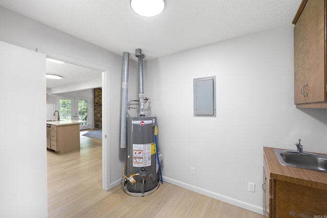 utilities featuring gas water heater, a sink, and electric panel