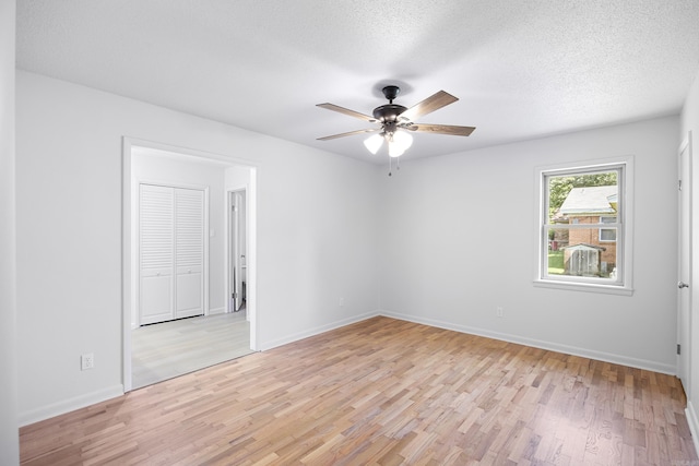 unfurnished room featuring a textured ceiling, light wood-style flooring, and baseboards