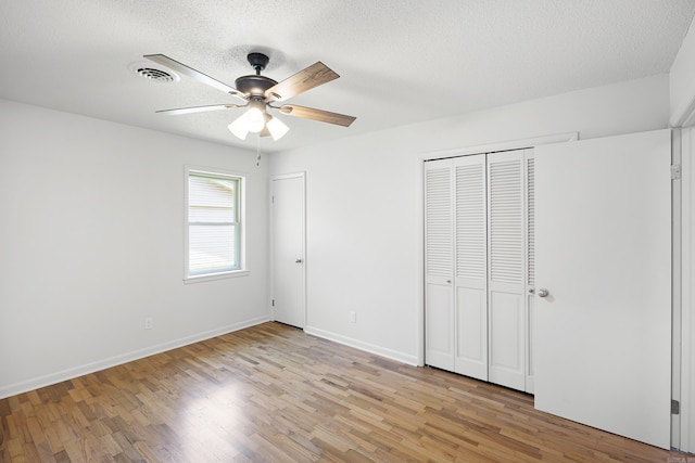 unfurnished bedroom with light wood-style flooring, baseboards, and a textured ceiling