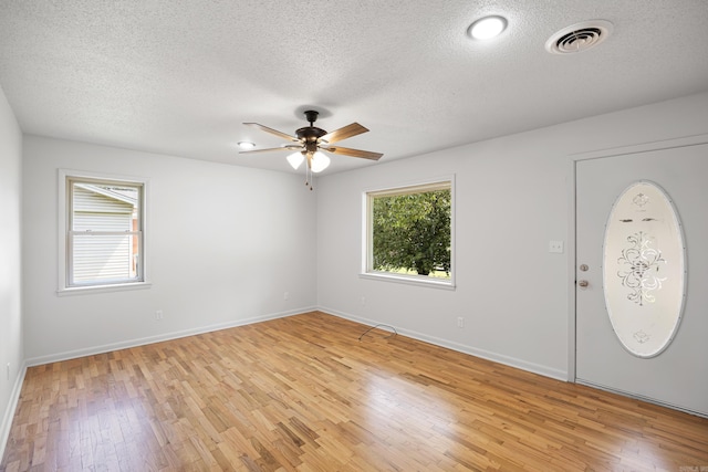 foyer featuring a healthy amount of sunlight, visible vents, light wood-style flooring, and baseboards